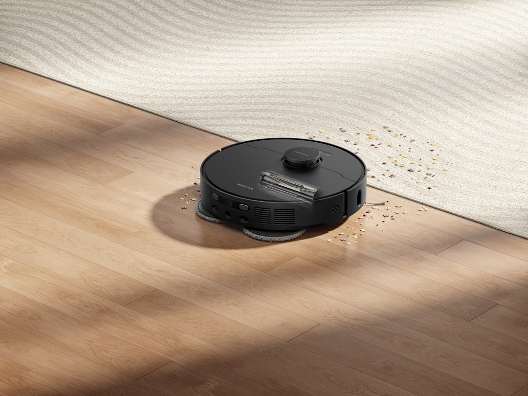 Dreame black robot mop and vacuum cleaner is removing debris on a wooden floor, combining power and elegant design.